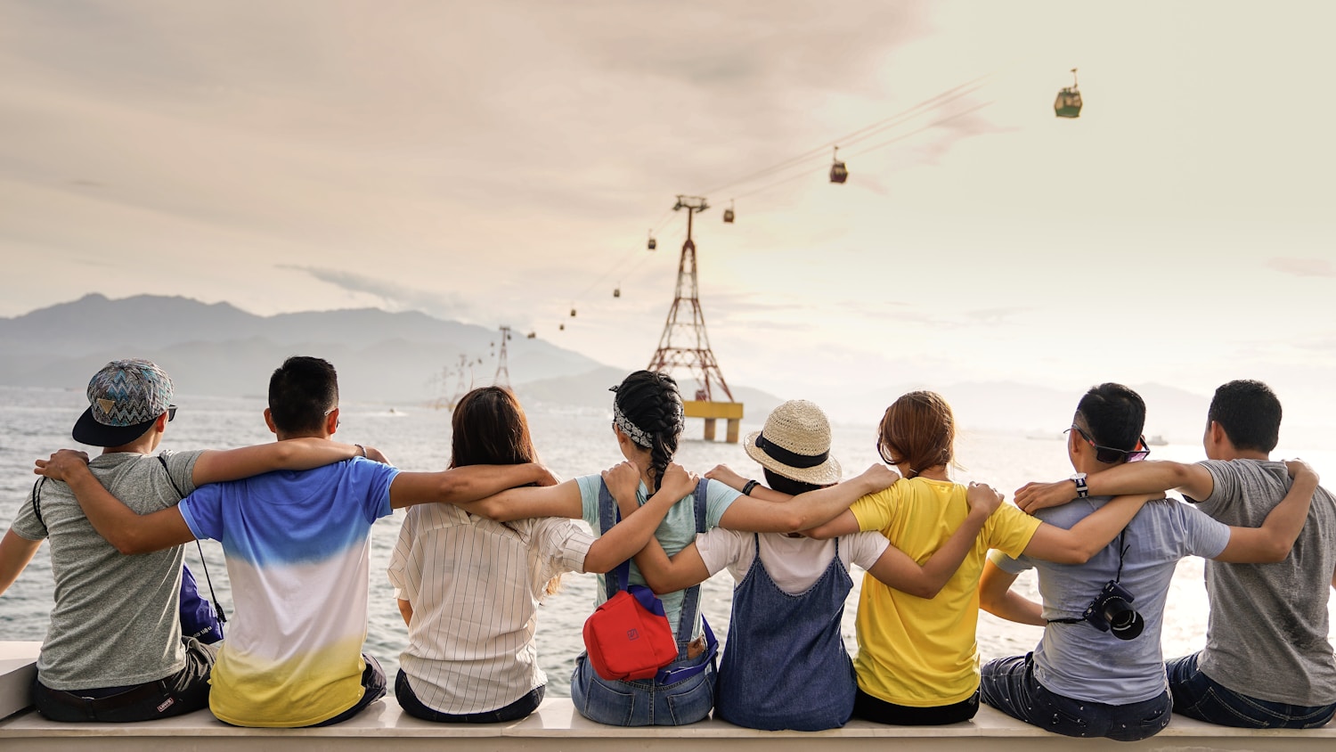 Friends with their arms around each other, sharing a moment by the sea